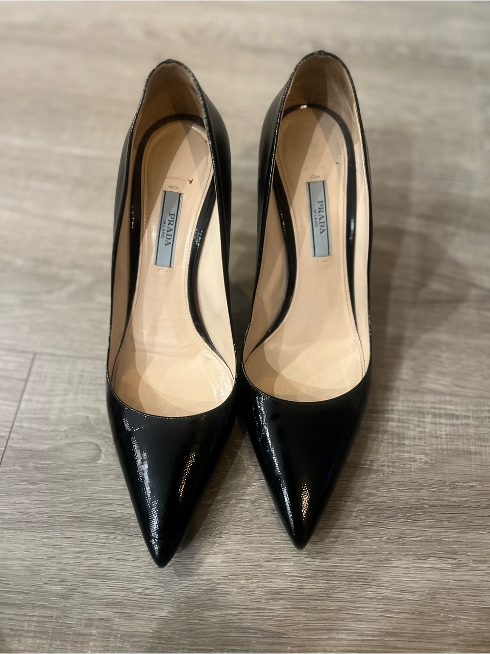 Prada Black Patent Saffiano Leather Pumps feature a glossy finish, pointed toe